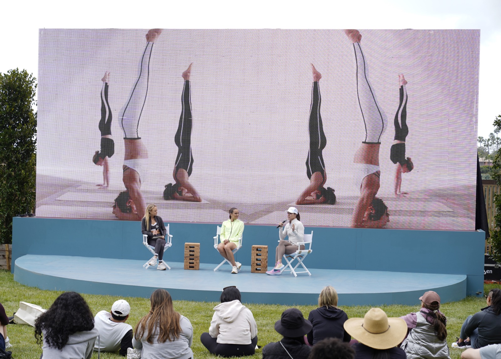 Nikki Kay moderating a wellness panel on an outdoor stage